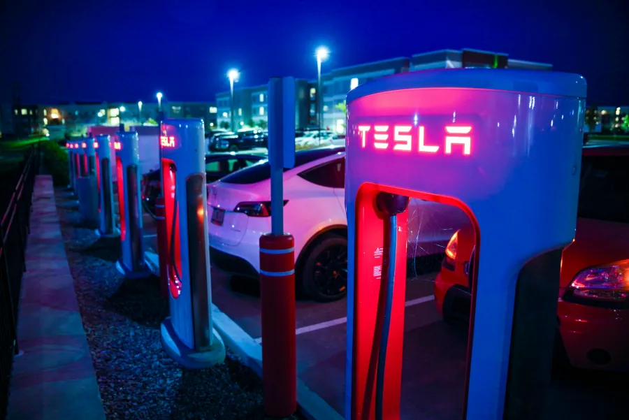 A row of Tesla Superchargers lit at night